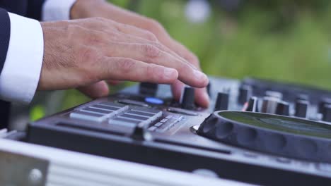 Close-up-of-DJ's-hands-pressing-buttons-on-a-music-table-at-wedding-party