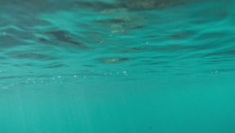 Mystical-clear-tropical-light-blue-water-reflects-abstract-brown-green-pattern-with-light-rays