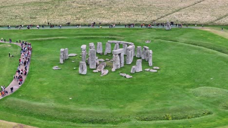 Drohnen-Luftaufnahme-Des-Prähistorischen-Steinmonuments-Stonehenge-Und-Touristen-In-Der-Grünen-Landschaft-Englands,-Großbritannien,-60 fps
