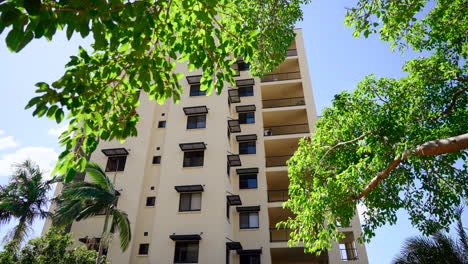 Retirada-De-La-Fachada-Del-Edificio-De-Apartamentos-Bajo-árboles-Tropicales-Con-Destellos-De-Lente