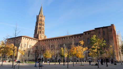 People-in-square-near-Basilica-of-Saint-Sernin-on-autumn-day,-Toulouse