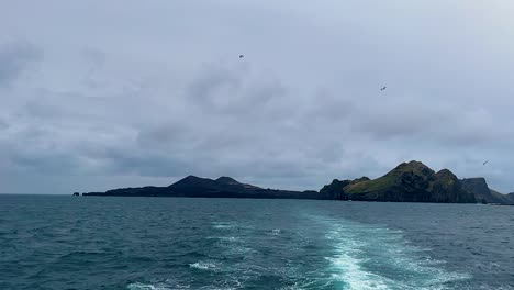 Boat-wake-with-view-of-Vestmannaeyjar-under-overcast-skies,-moody-and-serene