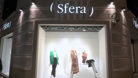Pedestrians-and-shoppers-walk-past-the-Spanish-clothing-manufacturing-and-brand-Sfera-store-at-nighttime
