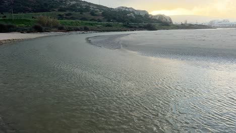 Along-the-coastal-region-of-Zahara,-Spain,-water-flows,-carving-a-channel-into-the-landscape