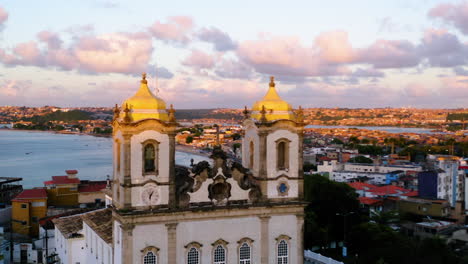 Luftaufnahme-Von-Der-Spitze-Der-Kirche-Nosso-Senhor-Do-Bonfim,-Der-Umgebenden-Stadt-Und-Dem-Meer-Im-Hintergrund,-Salvador,-Bahia,-Brasilien