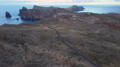 The-car-drives-along-a-winding-mountain-road,-with-breathtaking-views-of-the-ocean-coastline-and-a-blue-sky-above