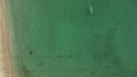 Aerial-view-of-buoys-on-the-beach-and-people-swimming-in-Huatulco,-Oaxaca