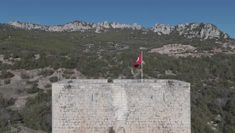 Drone-view-of-the-flag-on-the-castle-top-among-the-trees-on-the-mountain-top,-Belenkeşlik-Castle,-Turkey