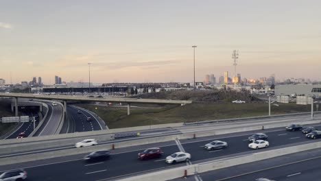 Carretera-De-Toronto-Con-Tráfico-De-Coches-Y-Horizonte-De-La-Ciudad-Al-Fondo-Al-Atardecer,-Canadá