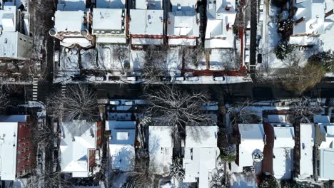 Vista-Aérea-De-Una-Calle-Cubierta-De-Nieve-Bordeada-De-Casas-Y-árboles-Desnudos