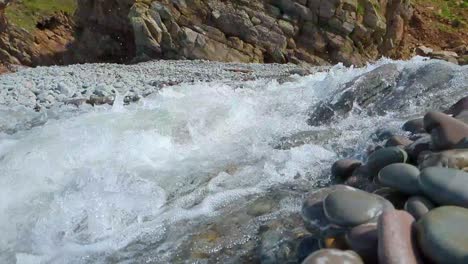 White-Water-River-Rushing-By-in-Slow-Motion-on-Rocky-Beach