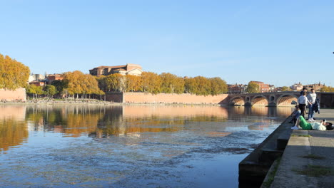 Quiet-scene-on-sunny-day,-people-resting-on-banks-of-Garonne-River,-Toulouse