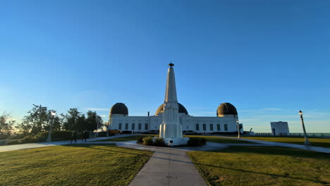 Architektonisches-Wahrzeichen-Von-Los-Angeles,-Kalifornien.-Menschen-Gehen-Im-Stadtpark-Mit-Glänzender-Morgenskyline-Spazieren,-Grasweg-Zum-Weißen-Denkmal