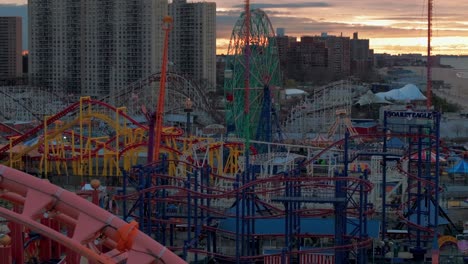 An-aerial-view-of-Coney-Island-amusement-park-in-Brooklyn,-NY-during-a-cloudy-but-colorful-sunrise