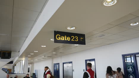 Terminal-23-Del-Aeropuerto,-Puerta-Veintitrés,-Cartel-En-Una-Concurrida-Zona-De-Espera-De-La-Sala-De-Embarque