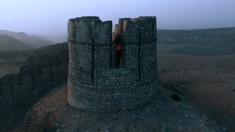 Vista-Por-Drones-De-Una-Turista-Parada-En-La-Cima-Del-Fuerte-Ranikot-En-Sindh,-Pakistán