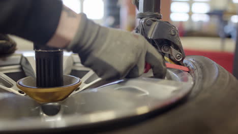 Tyre-technician-at-workshop-uses-machine-to-remove-tire-from-rim,-closeup