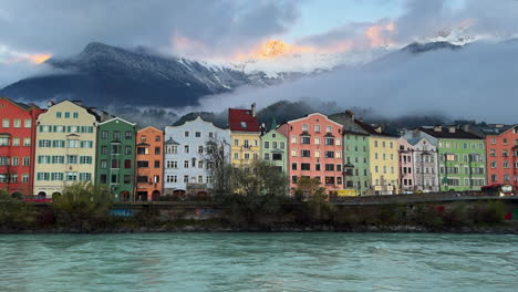Innsbruck-Austria-colorful-pastel-buildings-capital-Tyrol-Tyrolean-Alps-mountain-backdrop-the-bridge-over-the-Inn-River-cars-bikes-people-sunny-blue-sky-clouds-October-November-autumn-fall-static-wide