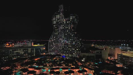 Una-Vista-Aérea-Del-Hotel-Y-Casino-Seminole-Hard-Rock-En-Forma-De-Guitarra-Iluminado-En-Modo-De-Espera-Con-Luces-Brillantes-Por-La-Noche