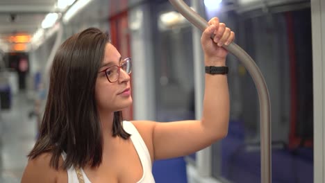 Woman-smiling-at-bus-holding-handgrip-for-safety-wile-travelling-in-a-train-means-of-transport