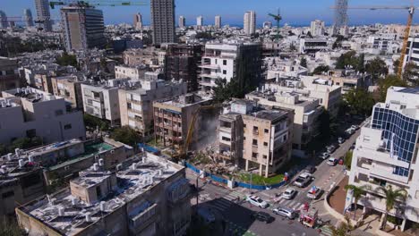 An-Old-Structure-Being-Dismantled-by-a-Long-Armed-Excavator-in-Tel-Aviv-Jaffa,-Israel---Drone-Flying-Forward