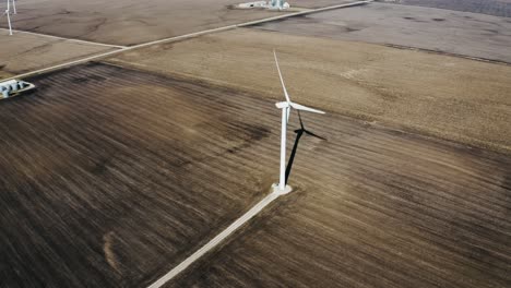 Drone-shot-of-a-wind-turbine-spinning-in-Iowa's-rural-farmland