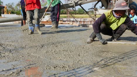 Wanderarbeiter-Füllen-Den-Bereich-Mit-Gemischtem-Zement-Und-Ebnen-Ihn-Gleichmäßig-Ein,-Bevor-Er-Für-Ein-Bauwerk-Am-Stadtrand-Von-Bangkok-Trocknet.