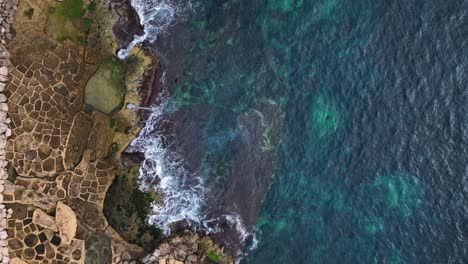 Flying-from-the-Mediterranean-Sea-to-the-shore-with-traditional-salt-pans-In-l-Jerma-Bay,-Marsaskala,-Malta