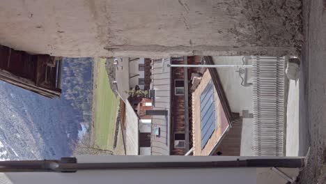 This-is-a-view-through-an-alley-across-roofs-towards-meadows-and-the-foot-of-a-mountain-in-Burgeis---Burgusio,-South-Tyrol,-Italy