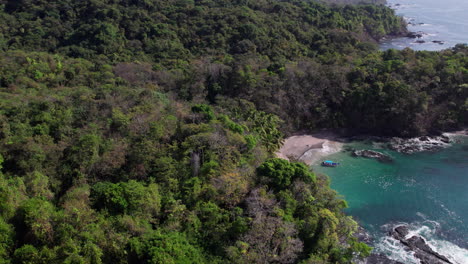 Aerial-establishing-shot-of-a-remote-beach-with-a-boat-at-Cebaco-Island