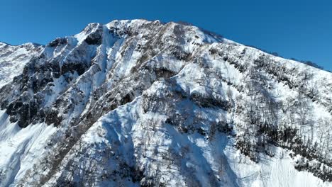 Aufsteigende-Weite,-Die-Schneebedeckte-Bergklippen-Hinauffliegt,-Eröffnungsaufnahme,-Die-Massive-Berge-Enthüllt