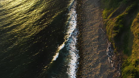 Aerial-view-of-Pacific-Ocean-waves-gently-rolling-onto-rocky-shore,-Oregon-Coast