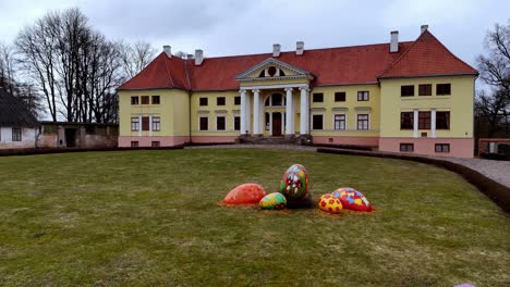 Durbe-castle-with-Easter-decorations-on-lawn,-aerial-view-on-an-overcast-day