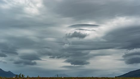 Dark-stormy-lenticular-clouds-form,-whirl,-and-move-fast-in-the-sky-carried-by-the-strong-wind
