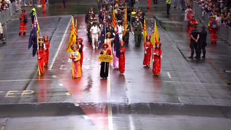 Mujeres-Vietnamitas-Vestidas-Con-Trajes-Tradicionales,-Seguidas-Por-Veteranos-De-Vietnam-Y-Sus-Familias,-Caminando-Por-La-Calle-Adelaide,-Participando-En-El-Desfile-Del-Día-De-Anzac,-En-Honor-A-La-Memoria-De-Quienes-Sirvieron.