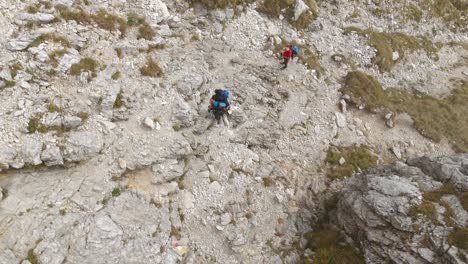 Aerial-View-Of-Backpackers-Hiking-Over-Mountain-Side-In-Lecco-Alps