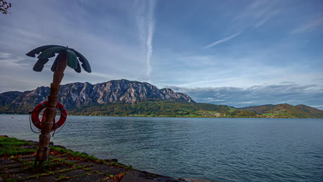 Panoramic-Attersee-lake-landscape-palm-tree-with-lifeguard-inflatable-Austria-beach-shore,-coastline