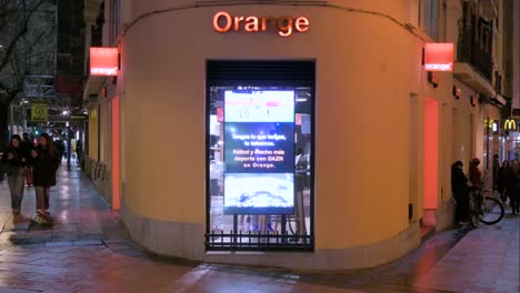 People-walk-past-the-French-multinational-telecommunications-corporation-and-phone-operator,-Orange-S