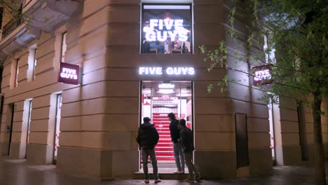 Customers-arrive-at-the-American-fast-food-casual-restaurant-chain-Five-Guys-during-nighttime