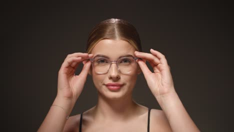 Cute-young-caucasian-woman-takes-off-glasses,-portrait-studio-shot