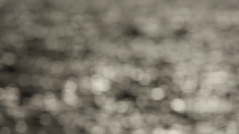 Abstract-grey-sparkling-background,-out-of-focus-sun-on-water