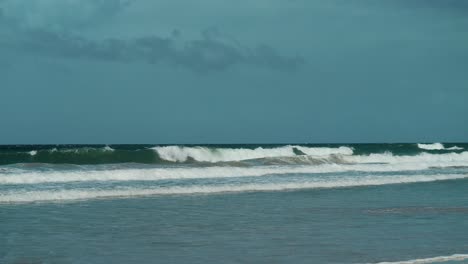 Ein-Malerischer-Tropischer-Strand-Mit-Rollenden-Wellen-Und-Klarem-Blauen-Himmel-In-Der-Ferne