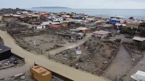 Low-flyover-of-rustic-charming-fishing-village,-Caleta-Chanaral,-Chile