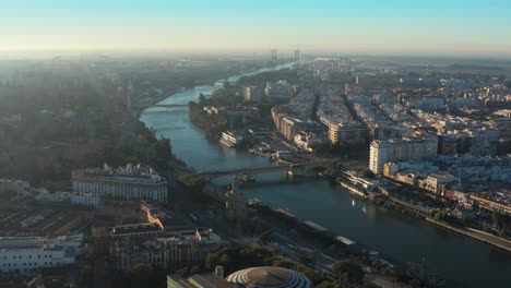Aerial-View-of-Seville,-Spain-on-Sunny-Afternoon,-River-Canal-and-Cityscape,-Drone-Shot