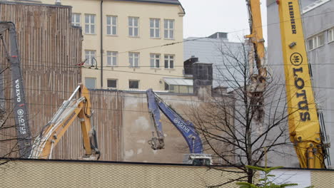 Heavy-duty-excavators-work-behind-wall-on-urban-construction-site