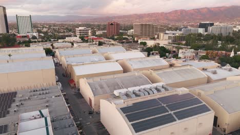 Aerial-Footage-of-Sound-Stages-in-Burbank-at-Warner-Brothers-Studios,-Flying-Over-Backlot-with-Golden-Mountains-on-Horizon