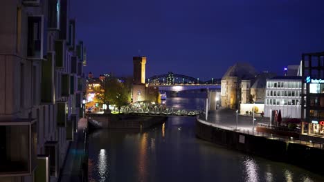 Experience-the-enchanting-allure-of-Cologne-by-night,-with-its-illuminated-skyline-and-majestic-bridges-casting-shimmering-reflections-on-the-Rhine-River