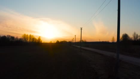 Fliegen-Neben-Stromleitungsmast-Während-Des-Hellen-Sonnenuntergangs,-Lettland