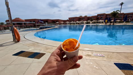 Enjoying-a-cup-of-ice-cream,-sorbet,-or-sherbet-by-the-pool