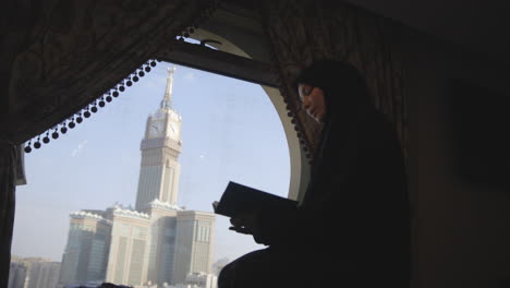 Young-Muslim-woman-reading-the-Koran-with-the-Royal-Clock-Tower-of-Mecca-in-the-background